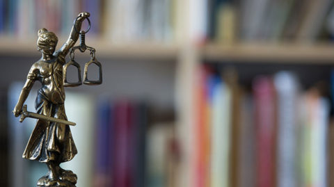 Justice Figurine in Front of Criminal Law Books